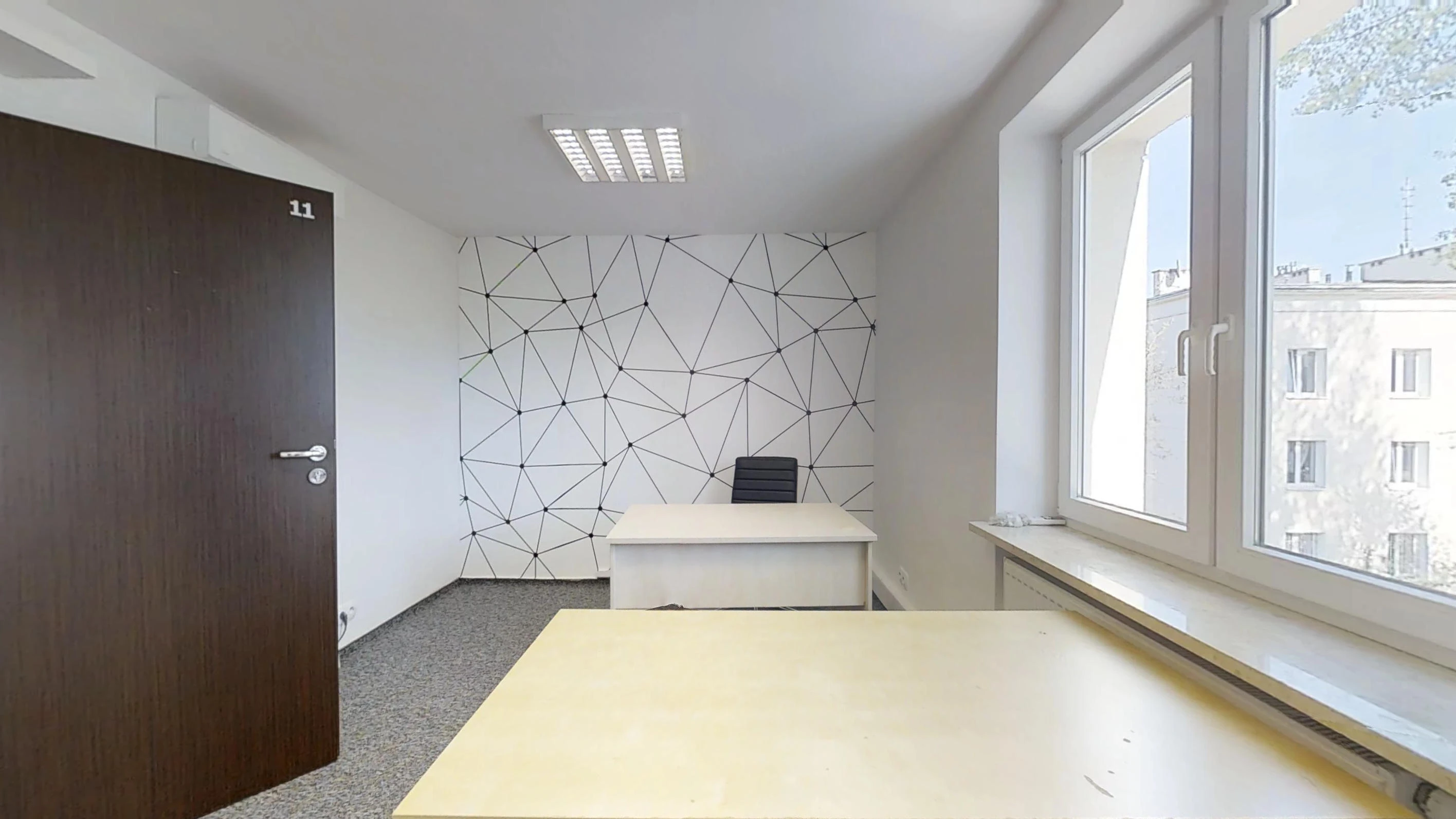Dwa biurka, geometryczny mural i okno w biurze